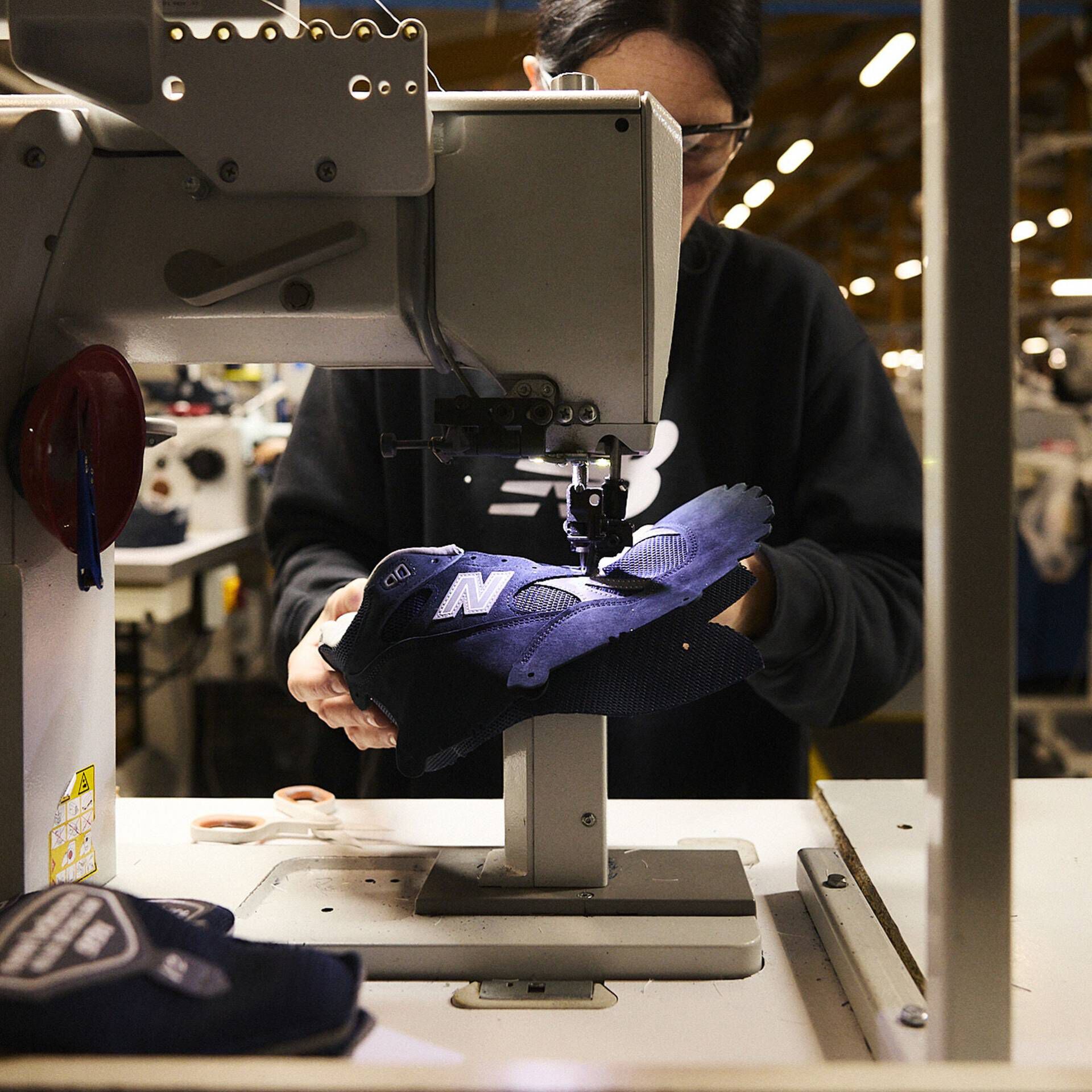 Female worker standing in the Flimby factory holding a MADE in UK 991 shoe.