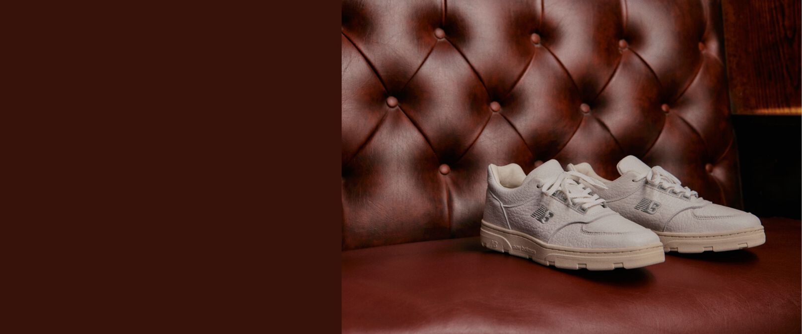 A pair of light blue MADE in UK 991 sneakers on a dark grey studio backdrop.