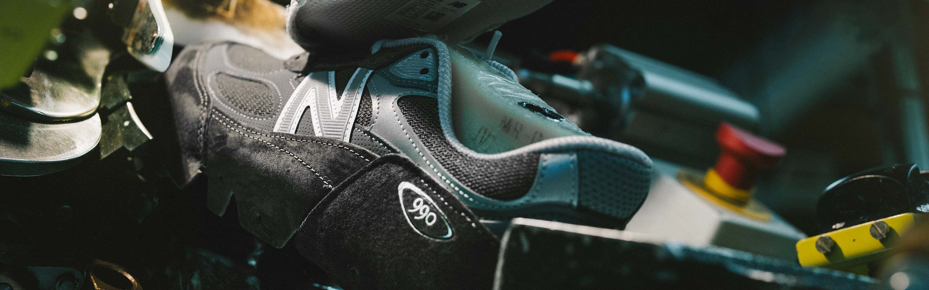 A New Balance sneaker sitting in equipment and being constructed in a factory setting.